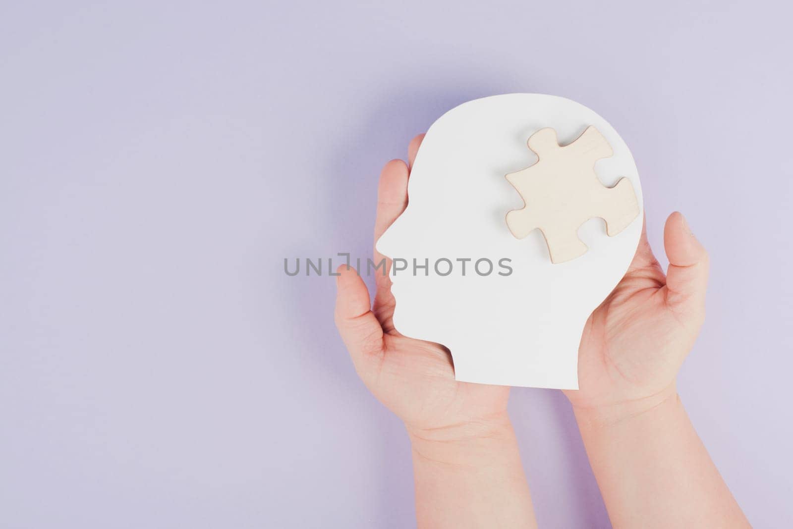 Holding a head with a puzzle piece, mental disease like Autism, Alzheimer, stroke awareness, brainstorming for ideas, memory problems