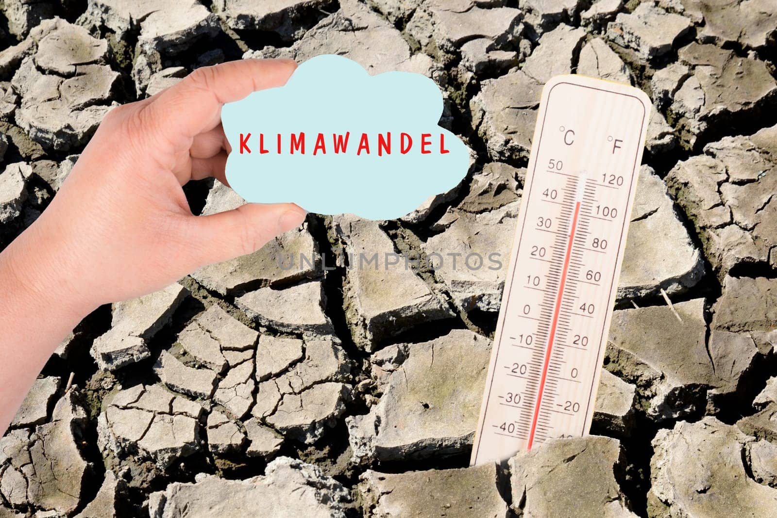 Dry earth with a thermometer, global warming concept, climate change is standing in german language on the cloud, environmental discussion, extreme weather