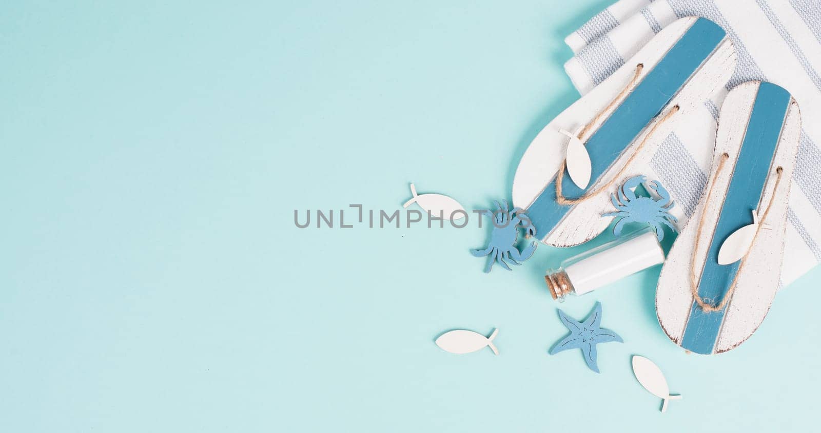 Blue colored summer and holiday background, flip flops, sea stars and a glass bootle with copy space, travel and tourism concept
