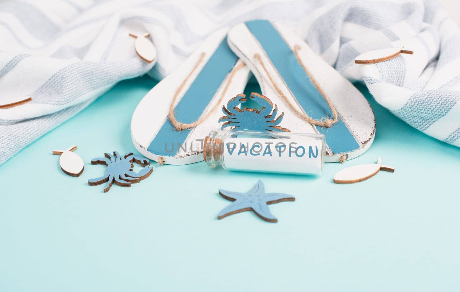 Blue colored summer and holiday background, flippers, sea stars and a glass bootle with the word vacation, travel and tourism concept