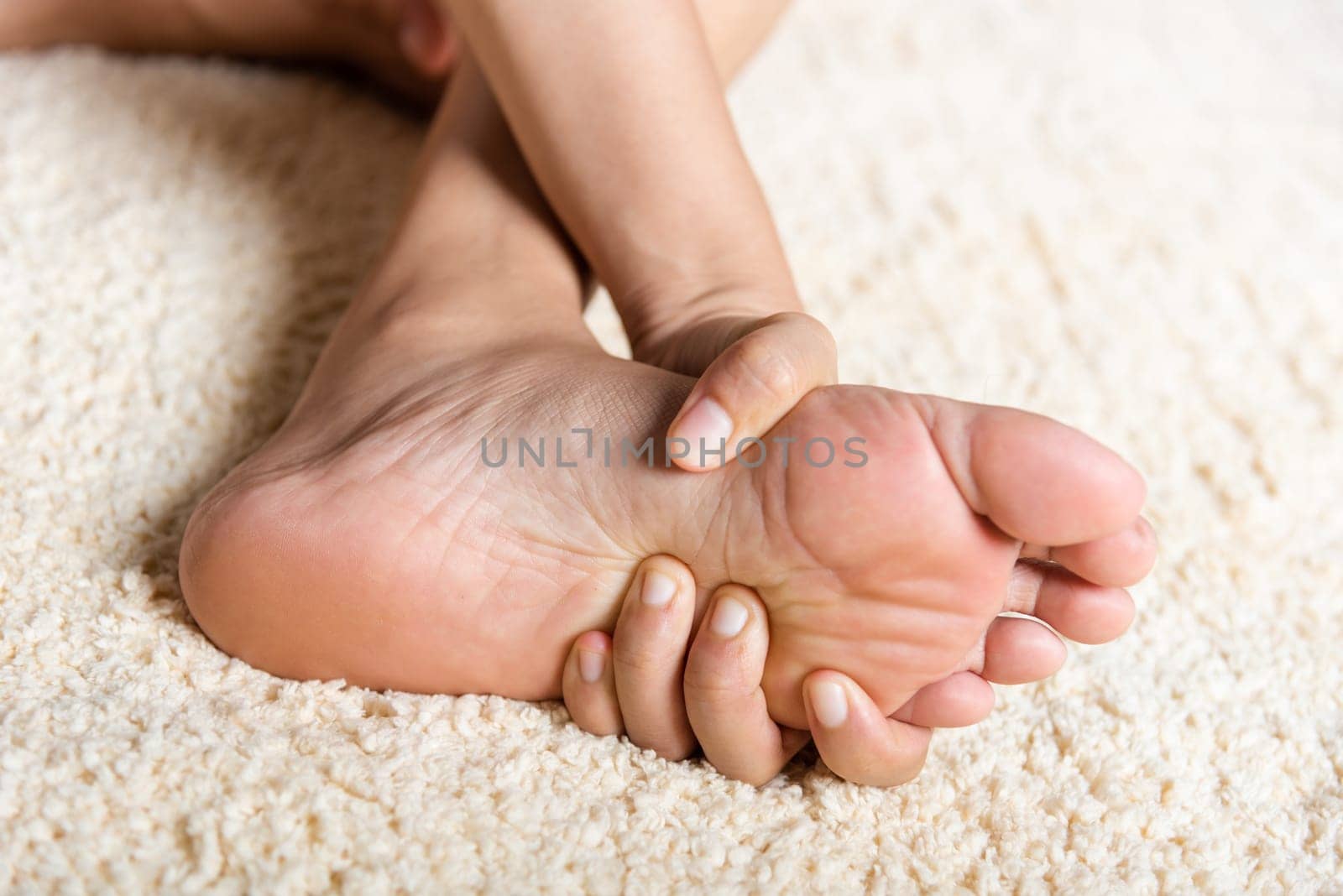 Foot pain, Asian woman feeling pain in her foot at home, female suffering from feet ache use hand massage relax muscle from soles in home interior, Healthcare problems and podiatry medical concept