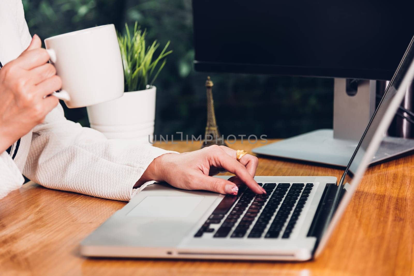 Beautiful business woman lifestyle working using laptop computer and holding coffee cup on hand while enjoying in modern desk office near window, work from home concept
