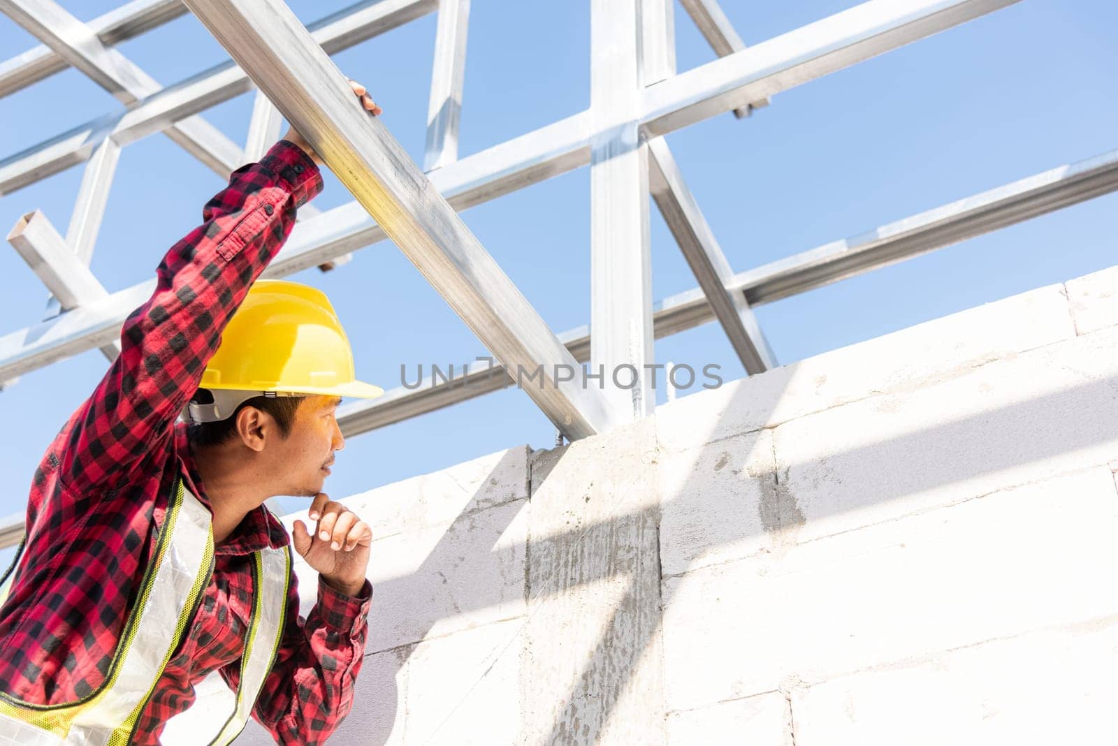 Construction worker or contractor checking house frame, worker roofer builder working on steel roof structure on building  construction site