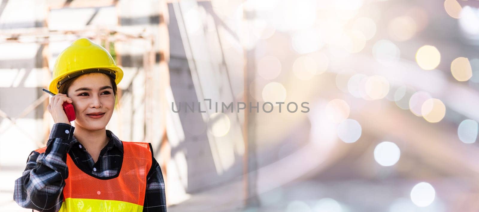 Asian engineer foreman architect worker woman working at building construction site talking with radio, engineering hold radio discuss operate and control worker employee to building construction