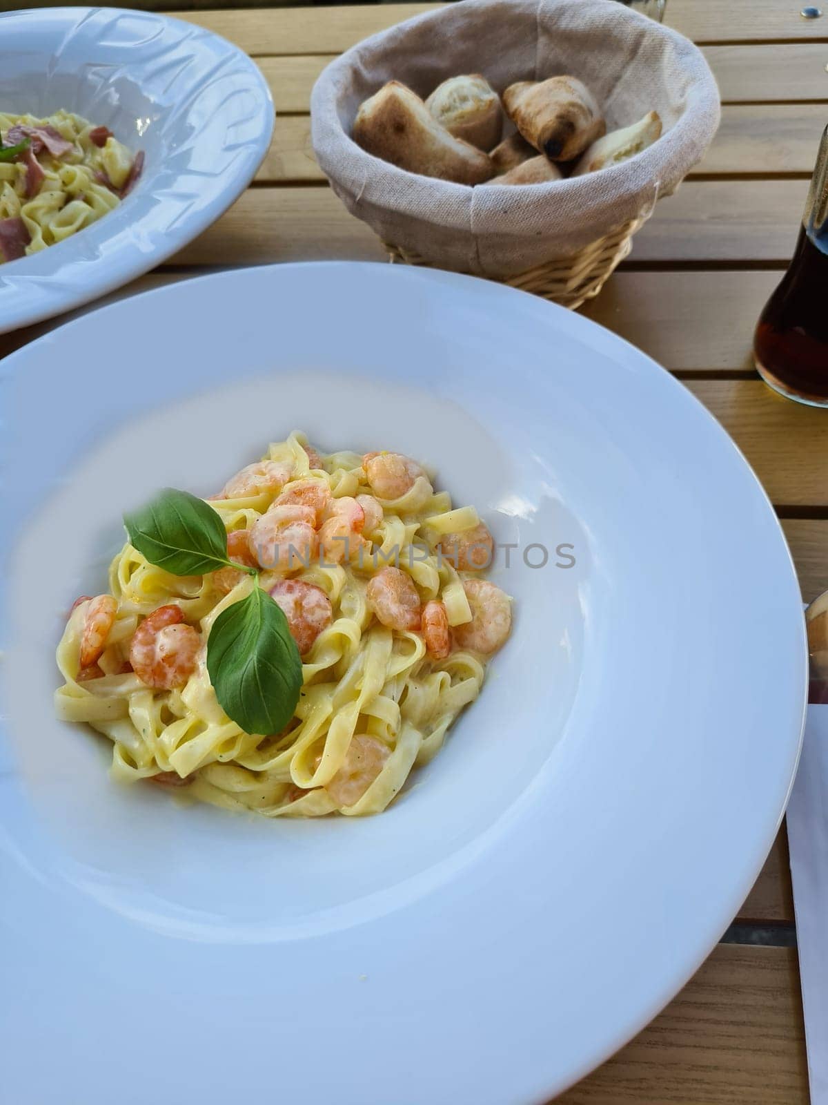 Plate of delicious pasta with shrimps on white wooden table, top view