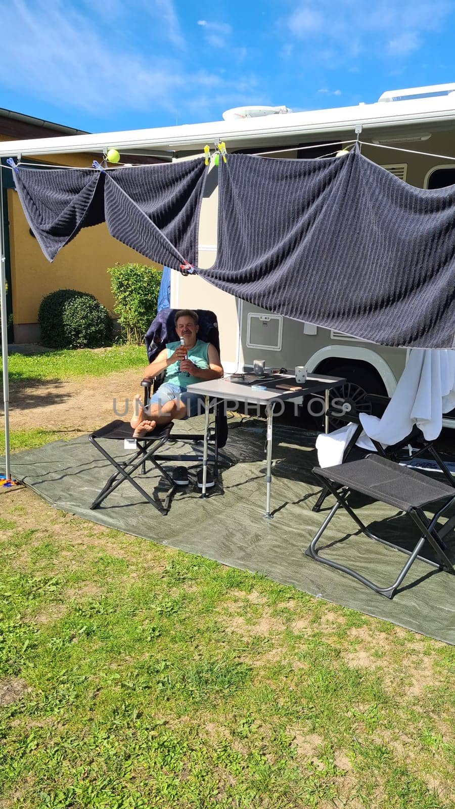 Man sits in front of his camper in a deck chair and relaxes