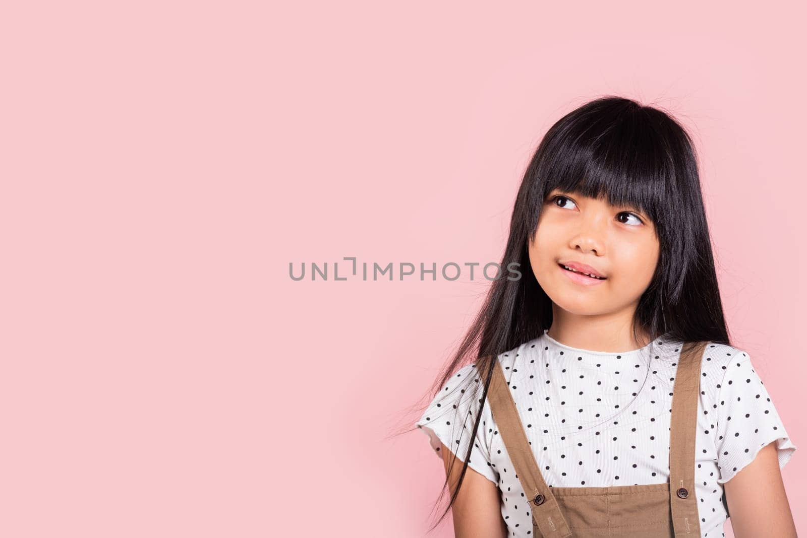 Asian little kid 10 years old looking away to side natural expression at studio shot isolated on pink background, Portrait of Happy child girl smiling staring away thinking