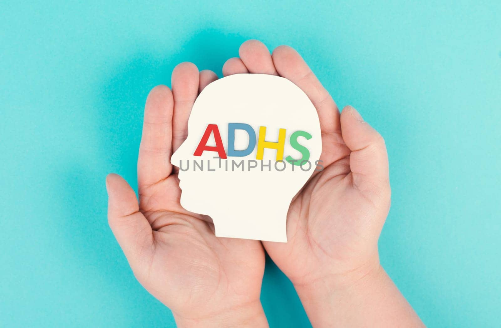 Hands holding a head with the german word ADHS which means attention deficit hyperactivity disorder, ADHD symptom, mental health