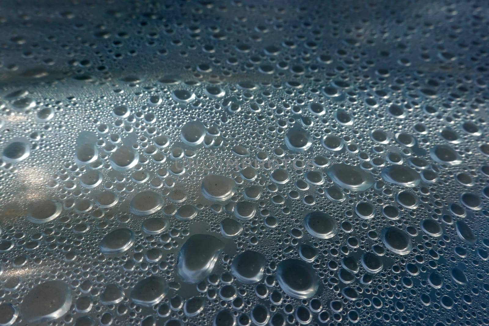 Kondenswasser-Tropfen bilden ein abstraktes Muster unter einer Plastikfolie