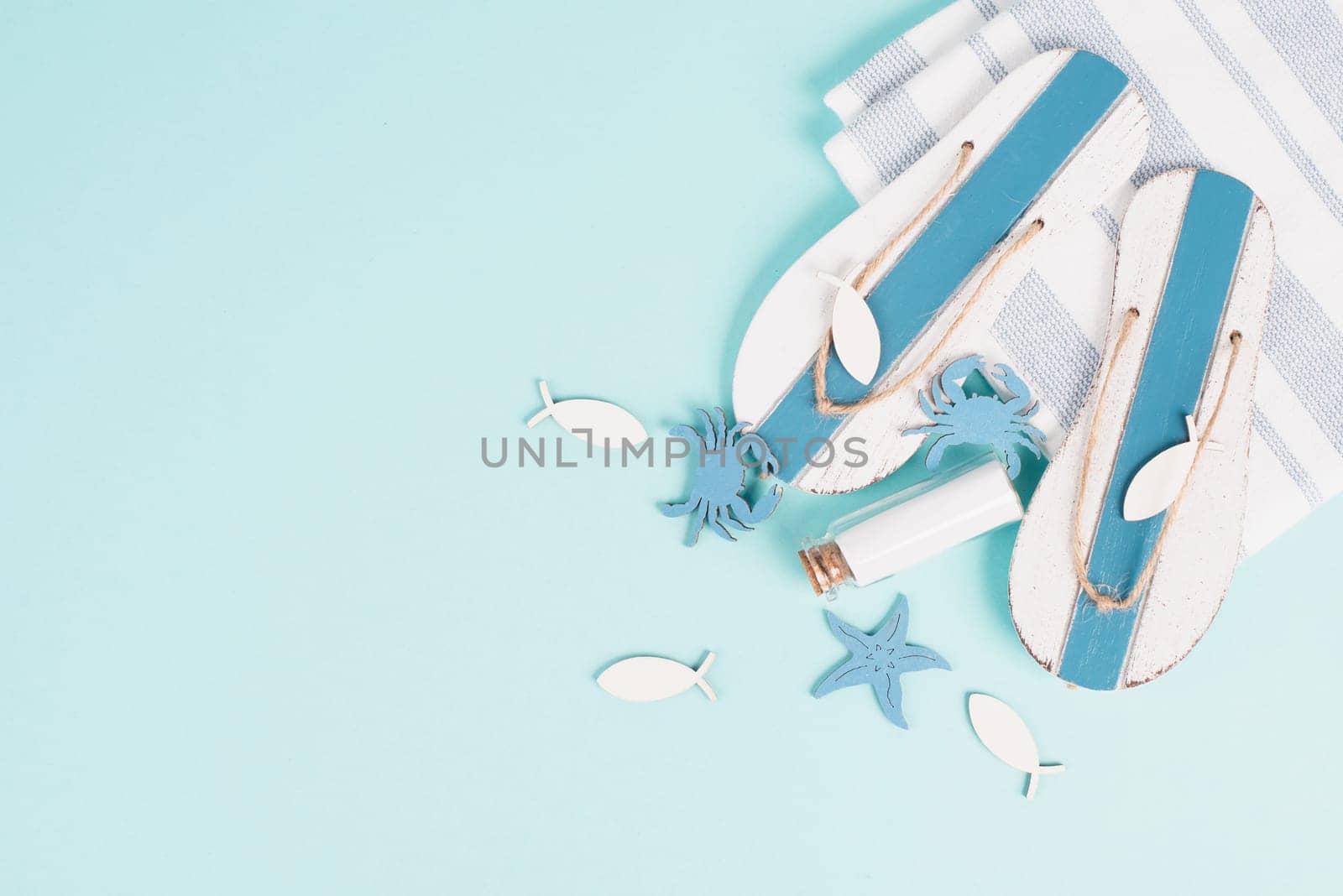 Blue colored summer and vacation background, flip flops, bottle and sea stars building a frame, copy space for text, holiday and tourism concept