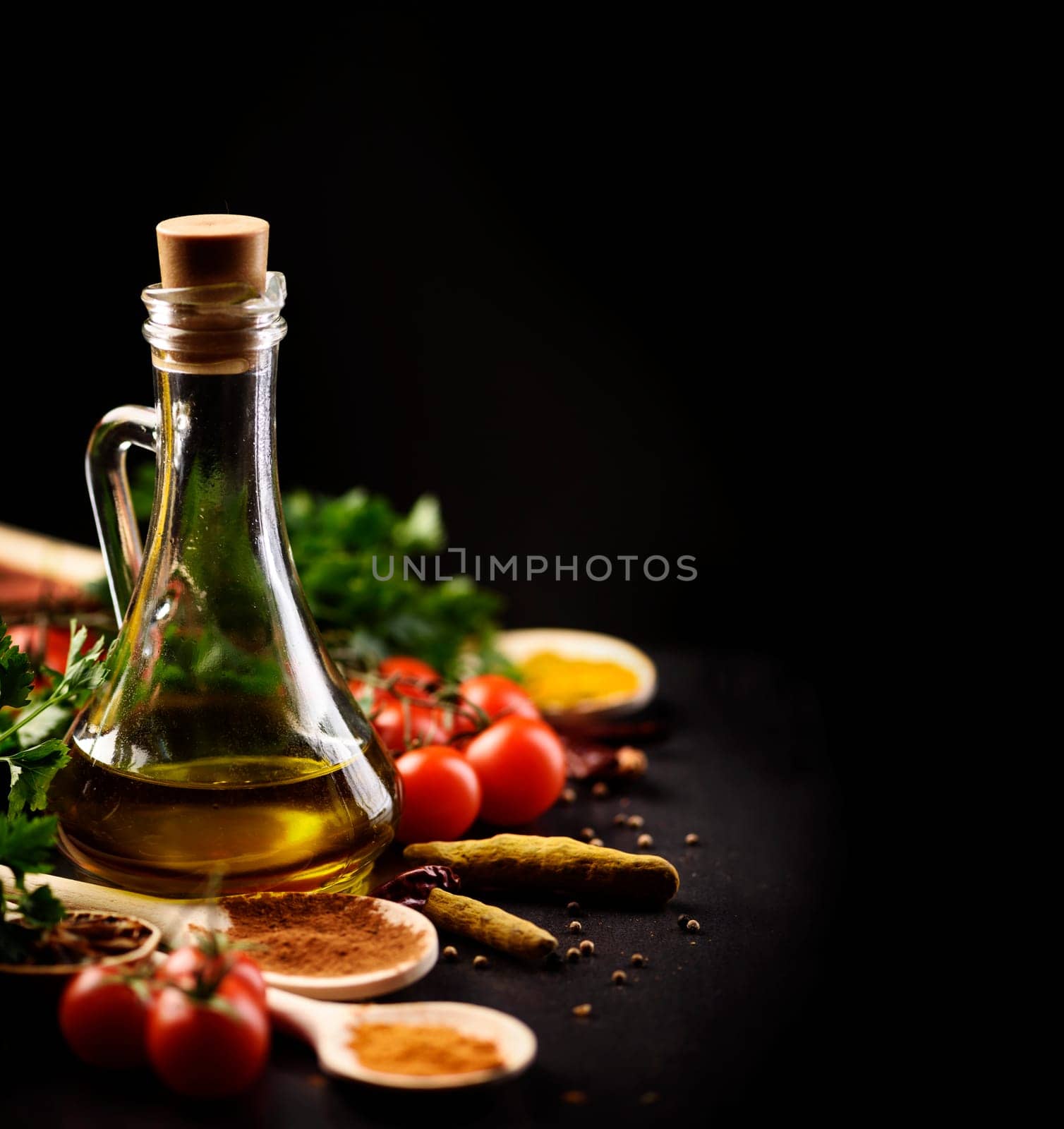 Olive oil and various spices on black rustic background