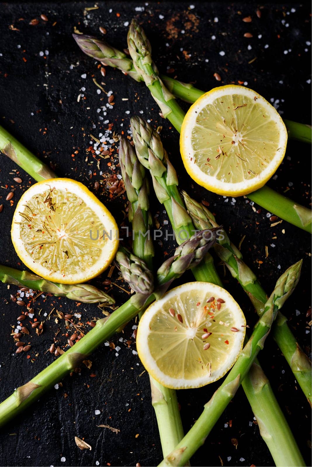 Asparagus with lemon and spices on black rustic plate