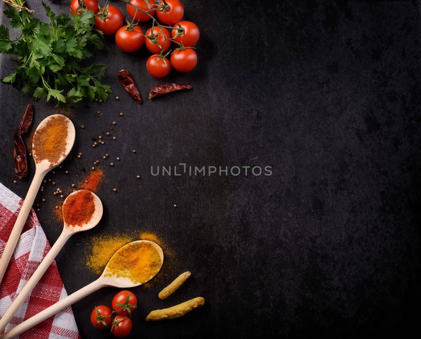 Various spices on rustic black background with copyspace.