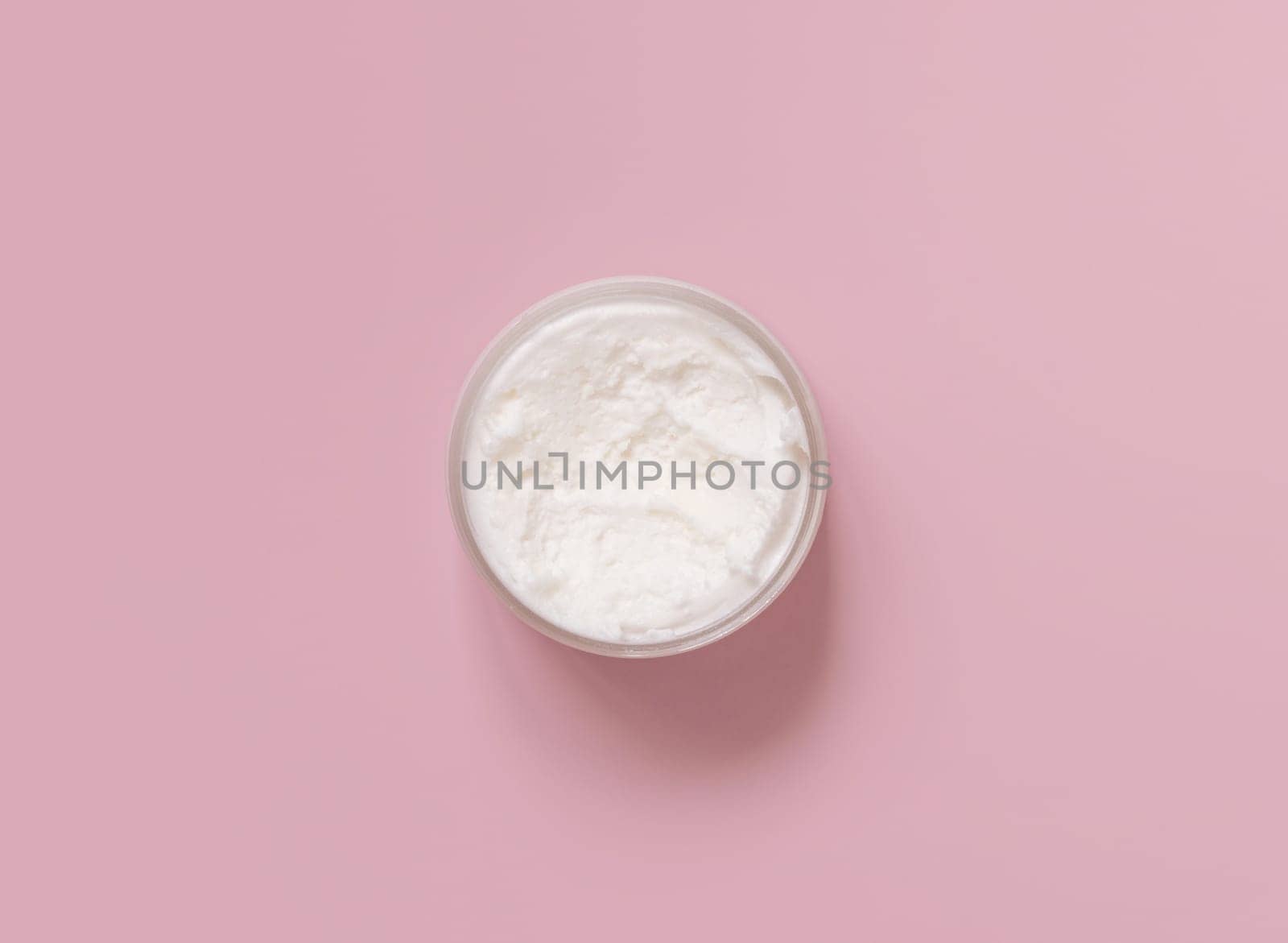 Homemade cream in plastic jar on light pink top view. Brand packaging mockup. Organic natural cosmetics for skin and hair care