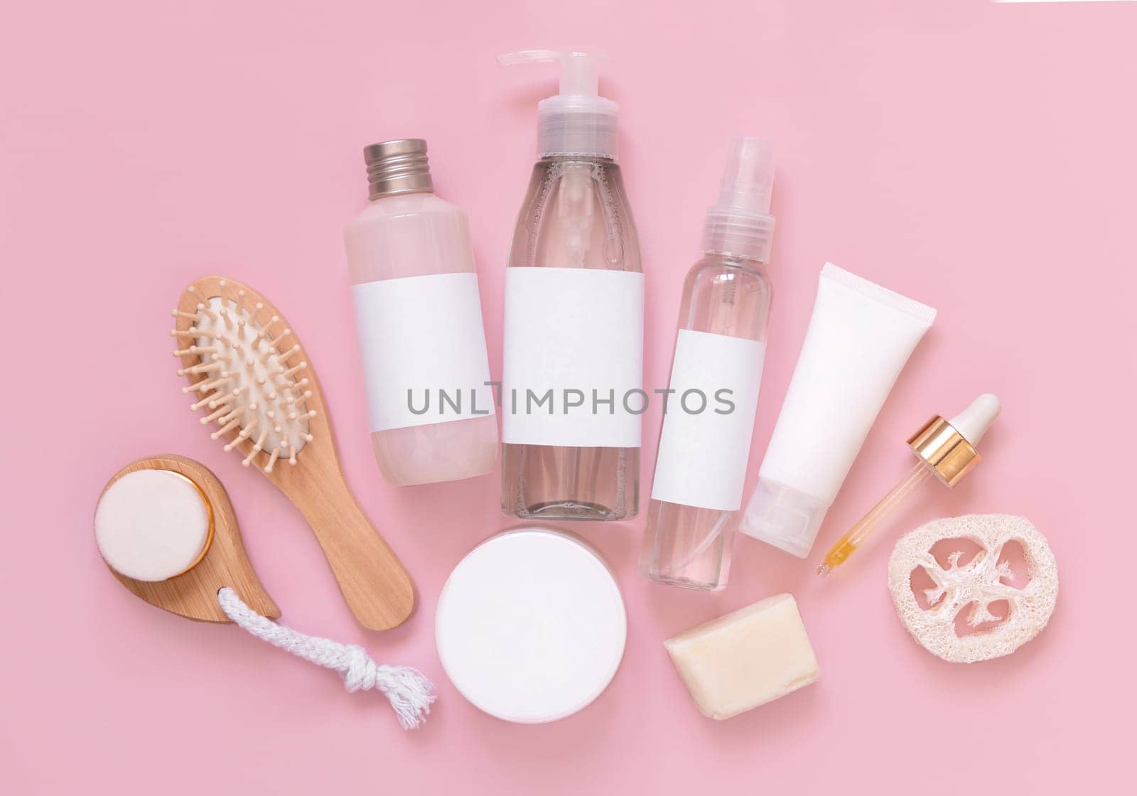 Homemade organic cosmetics in tubes and bottles and eco friendly accessories on pink flat lay, copy space. Top view of natural beauty products for hair and skin care