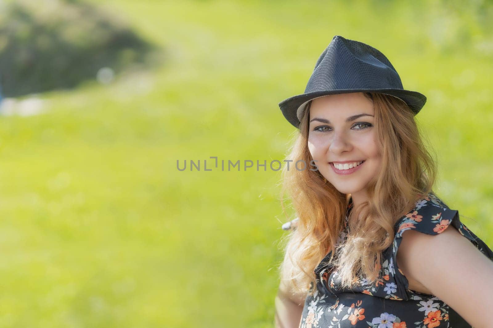 Portrait of attractive  young woman in black straw hat posing outdoors in summer day. Horizontally.