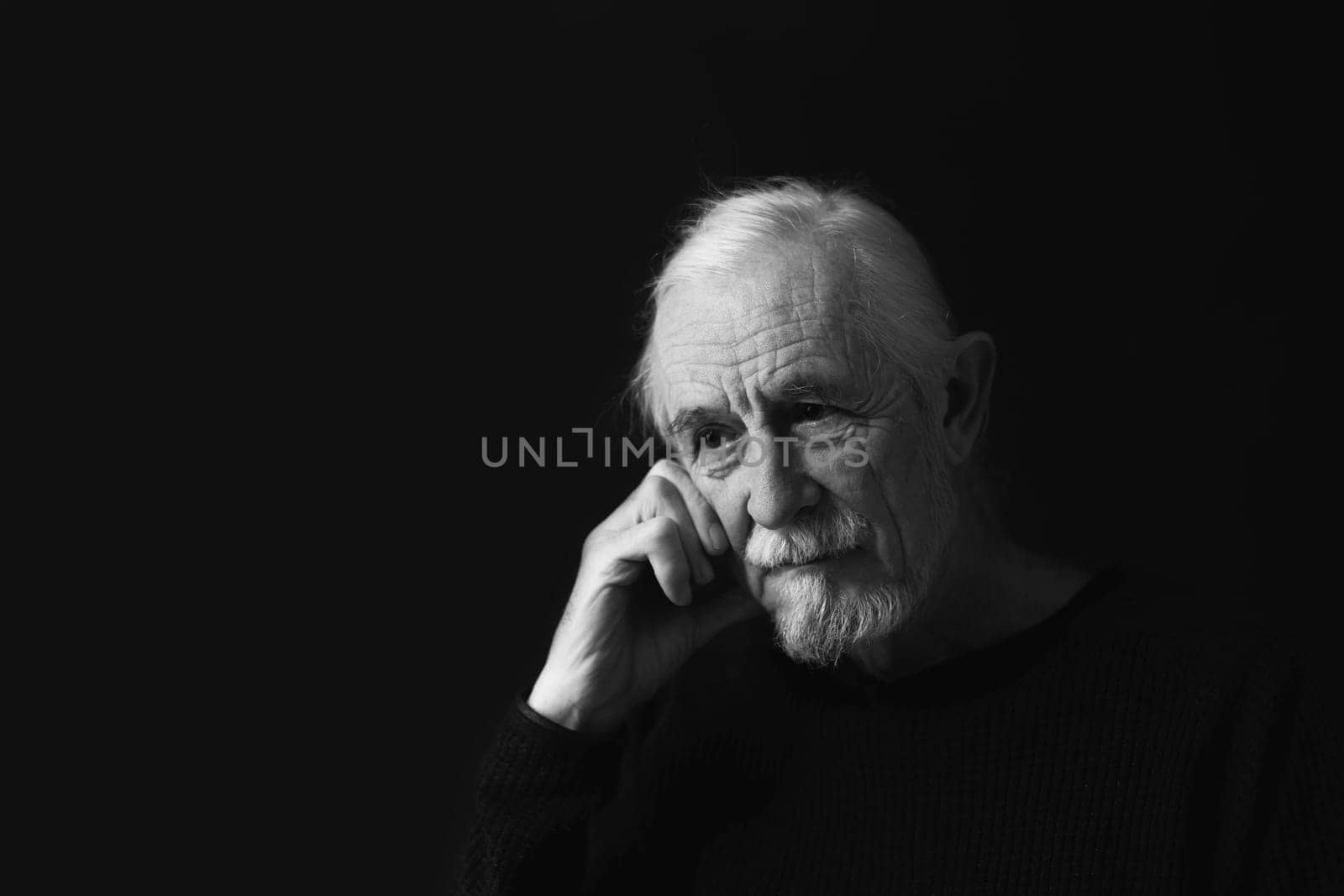 Low key studio black and white portrait of sad beautiful gray hair old man.