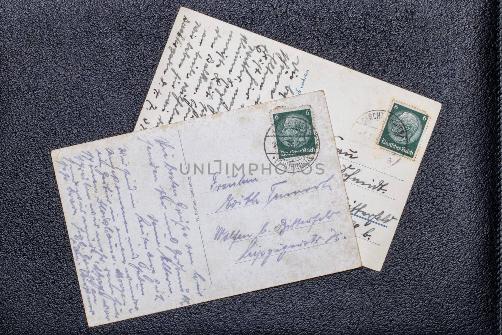 Potsdam, Germany - MAY 06, 2022. Old postcards from 1935 and 1939 with stamps showing the portrait of the German Reich President Paul von Hindenburg, Germany, Third Reich. Black background.