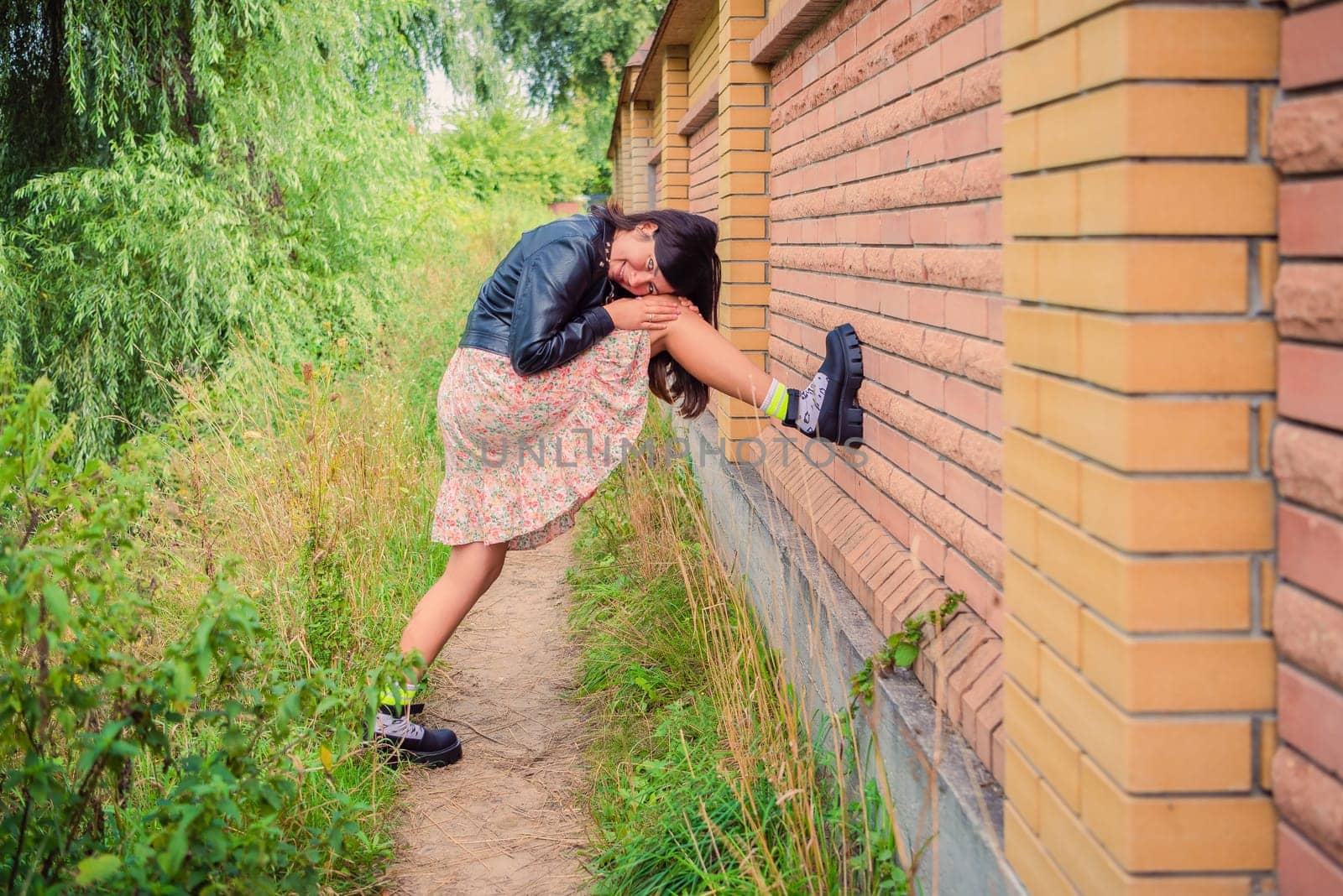 A young girl put her foot on a brick fence in the park