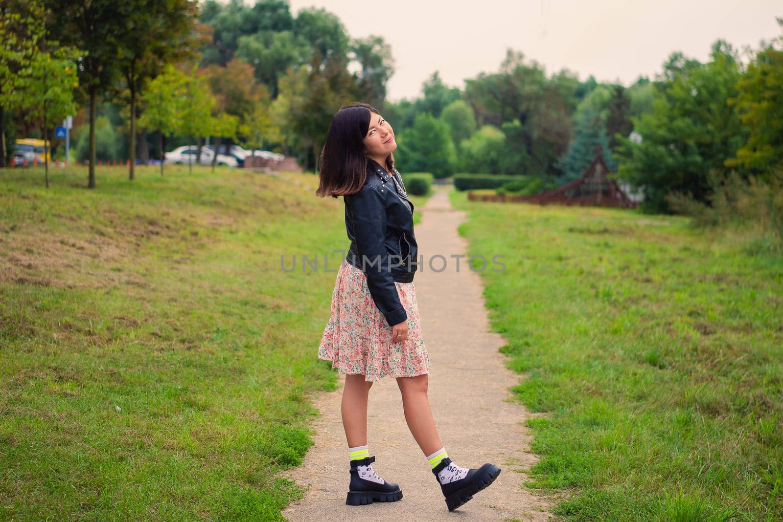 Smiling young girl pulled her straight leg to the heel while standing on a path in a green park