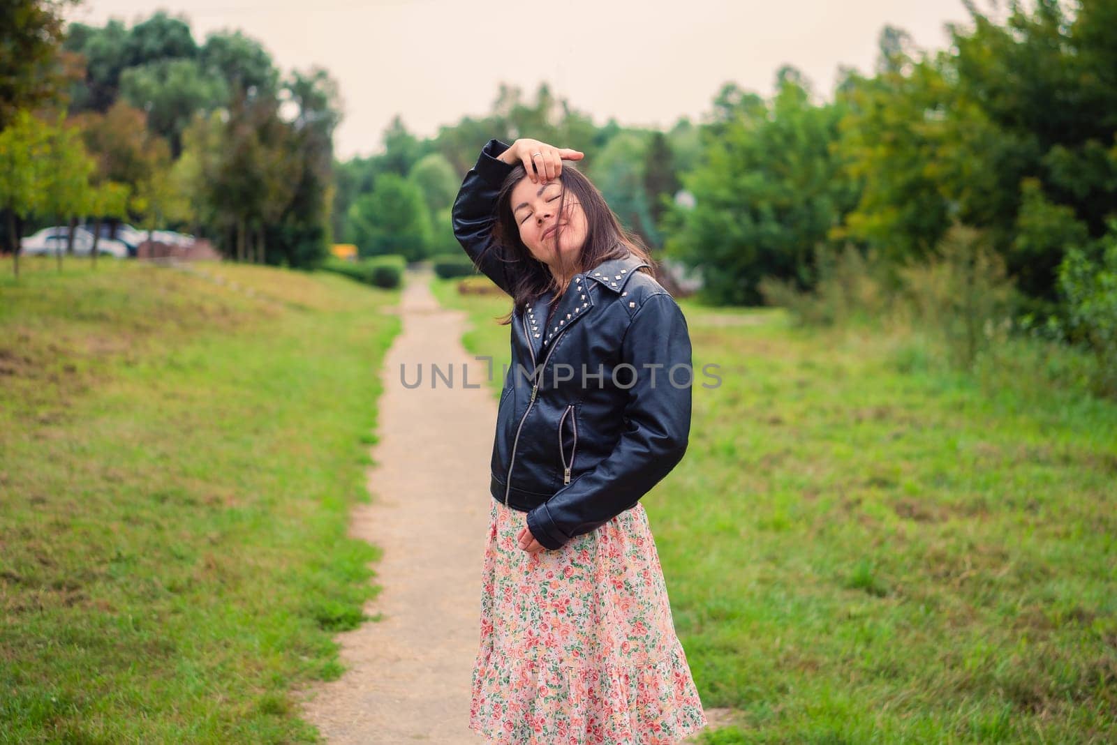the girl closed her eyes and straightens her long dark hair in the park