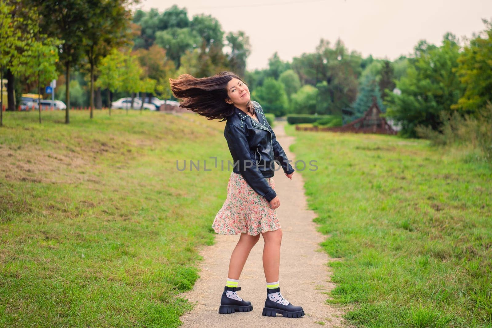 beautiful young smiling woman twists her head with long black hair in nature