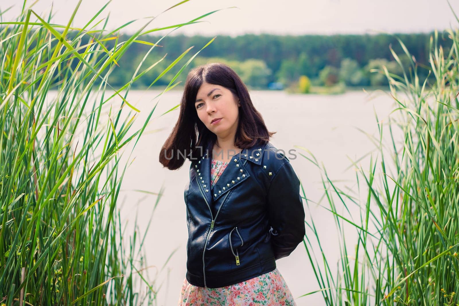 portrait of a young woman in a black jacket on the shore of a large lake