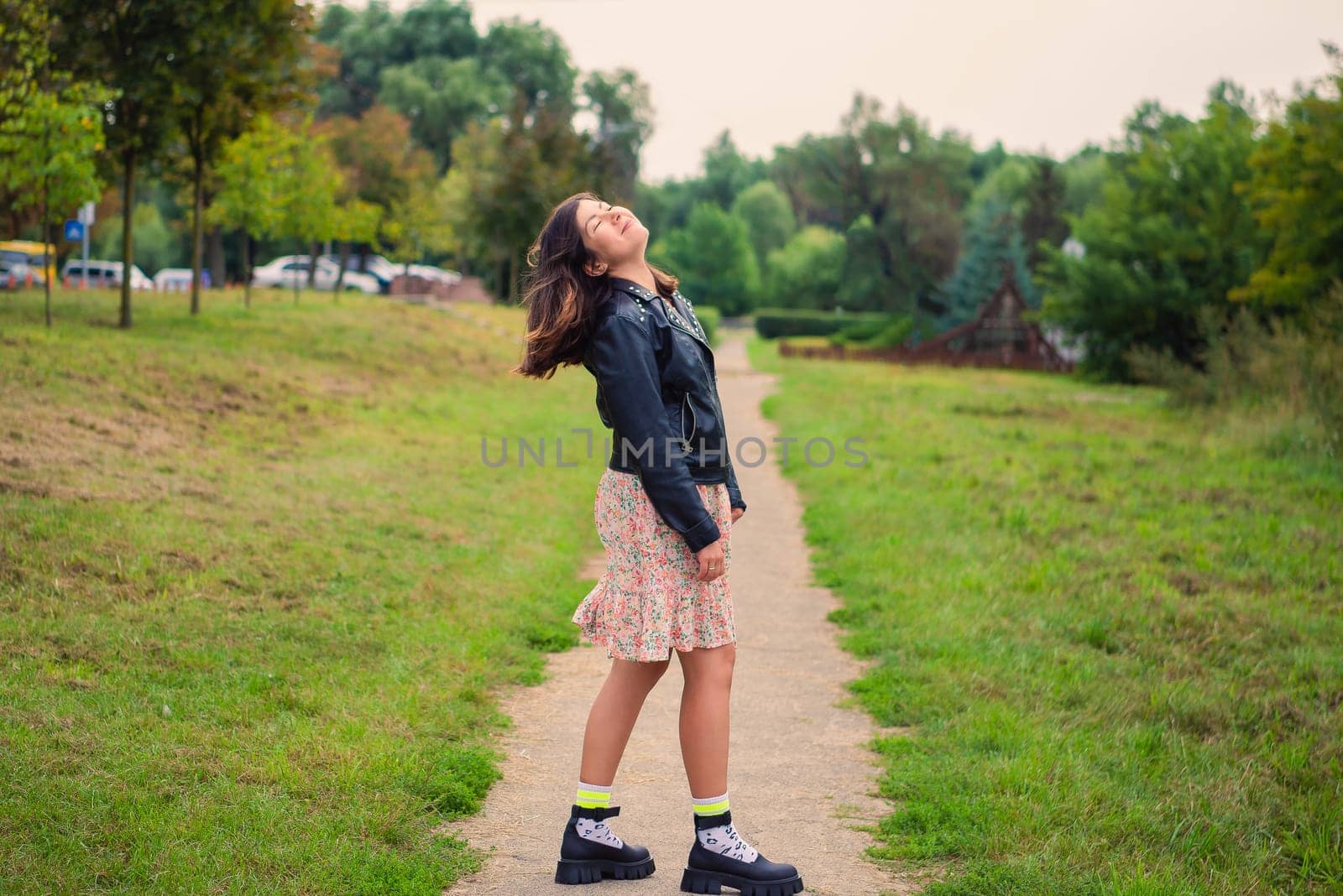 very beautiful young girl smiling, closing her eyes and raising her head up in a green park
