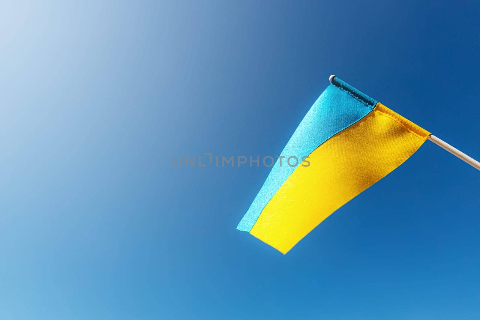 Large bicolor yellow blue Ukrainian state flag, national symbol fluttering, waving in wind against blue sky on sunny day. Kyiv city, capital of Ukraine, Independence Constitution Day, National holiday