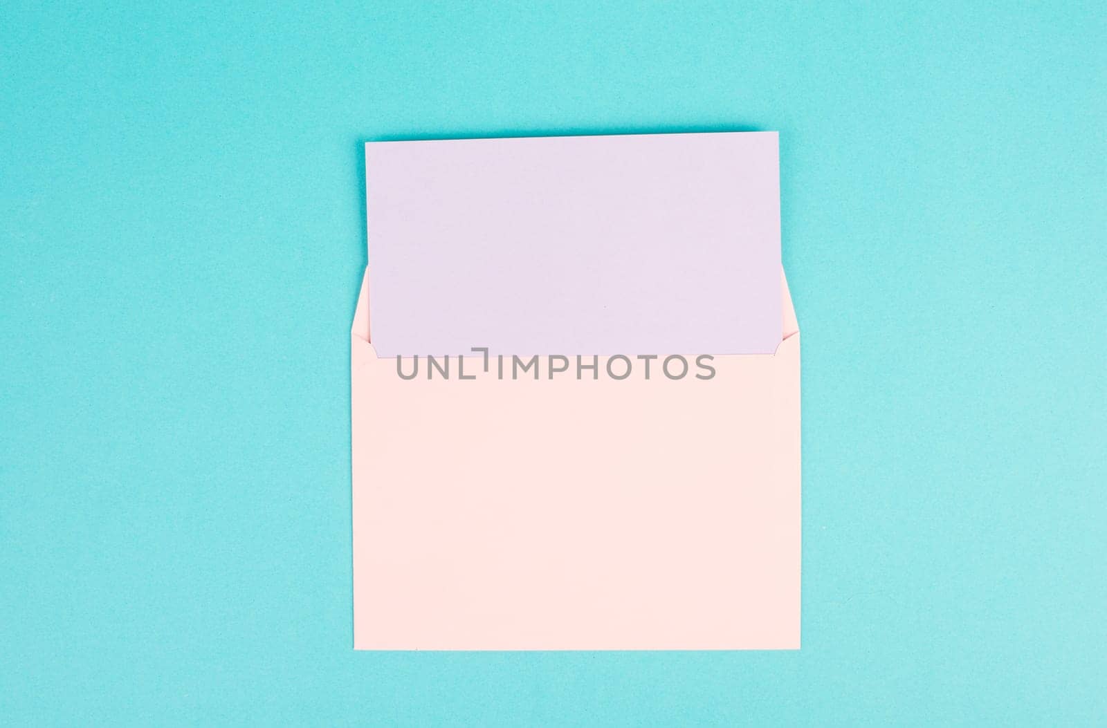 Pink colored envelope with an empty with paper on a turquoise background, copy space for text, greeting card, communication and announcement concept, reminder