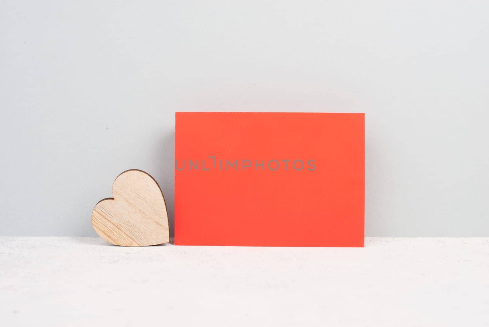 Red envelope with an empty paper, wooden heart, textured background, birthday, mothers day, fathers day and valintines day greeting card