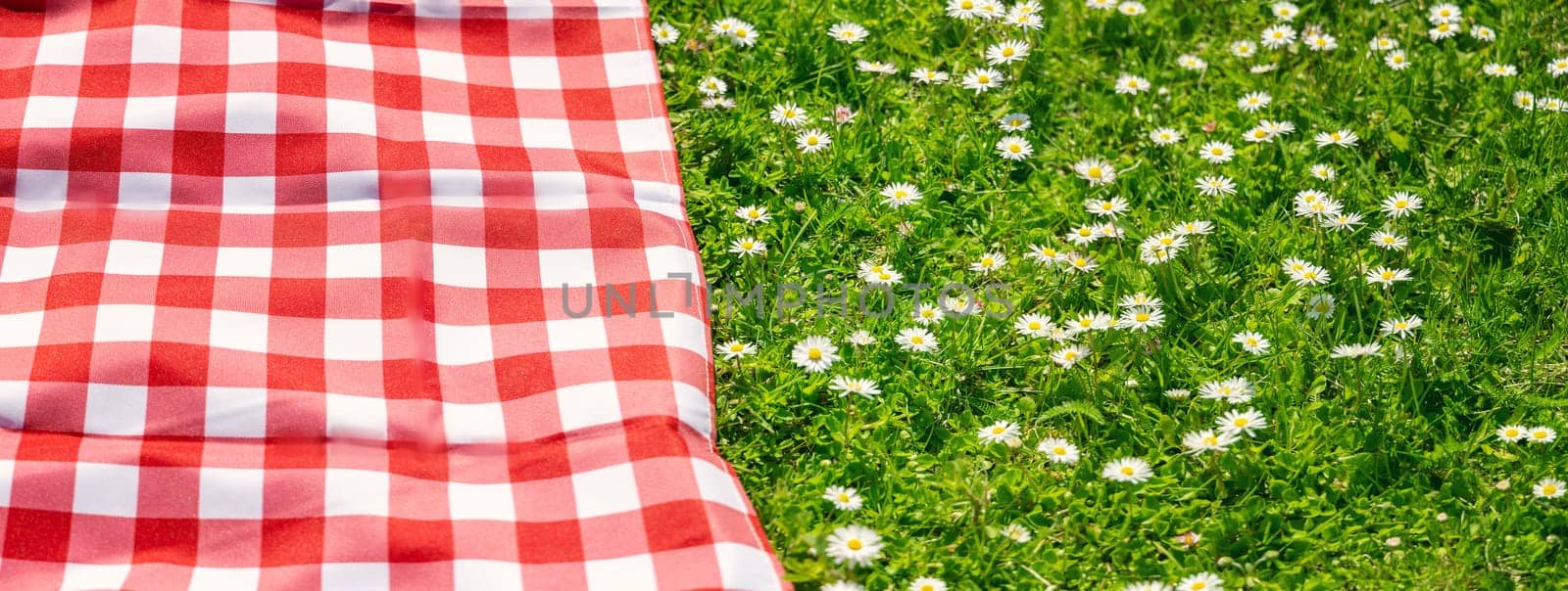 Picnic duvet on the meadow with green grass and spring flowers. Concept of tourism and leisure.