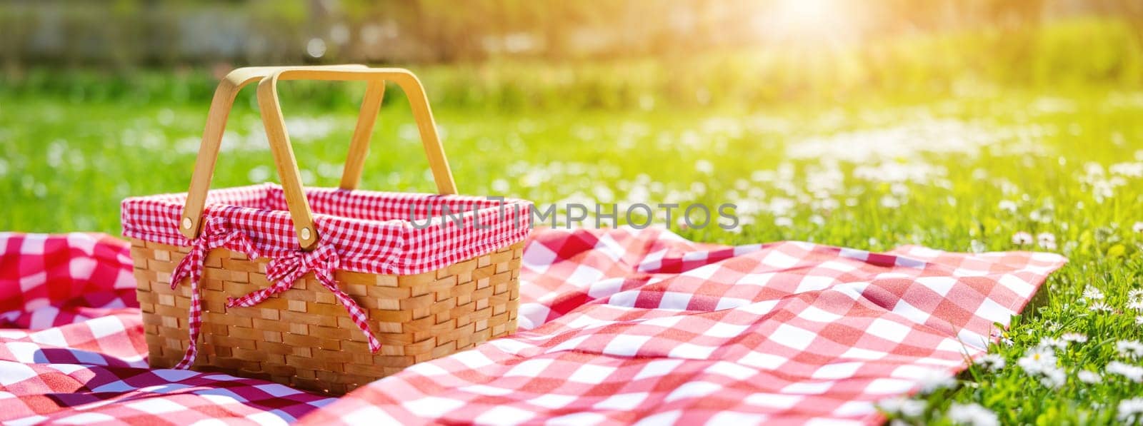 Picnic duvet with empty bascket on the meadow in nature. Panoramic view. Concept of leisure and family weekend.