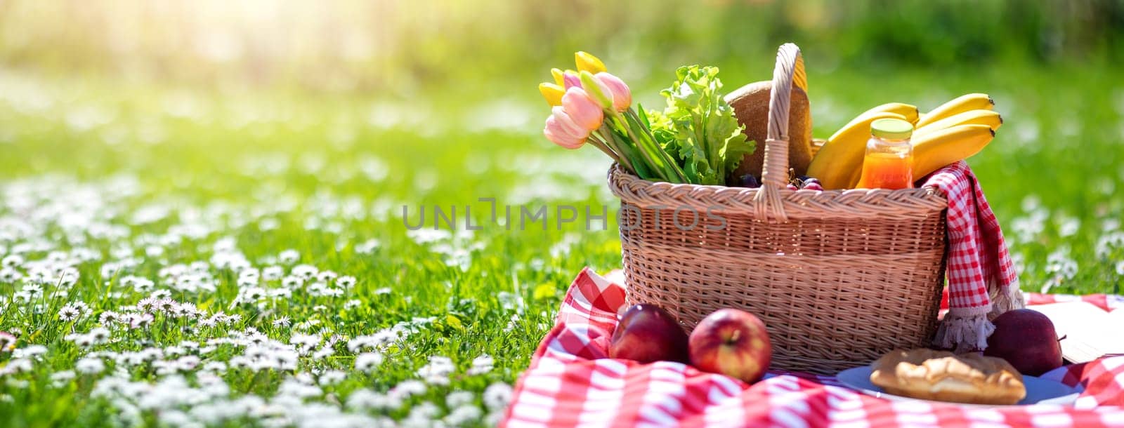 Picnic bascket on the duvet on the meadow in the nature. Concept of leisure, romantic dinner and family weekend.