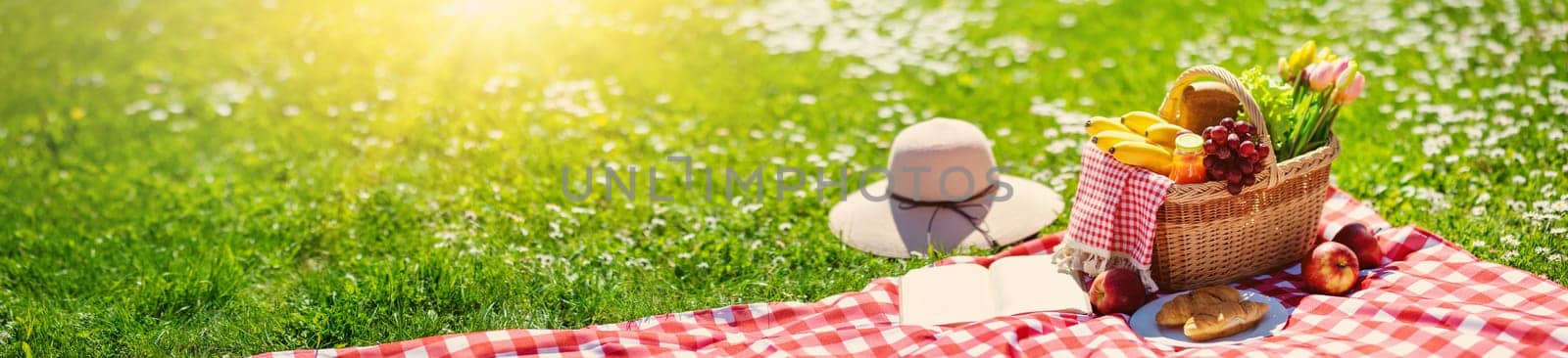 Picnic bascket on the duvet on the meadow in the nature. Concept of leisure, romantic dinner and family weekend.
