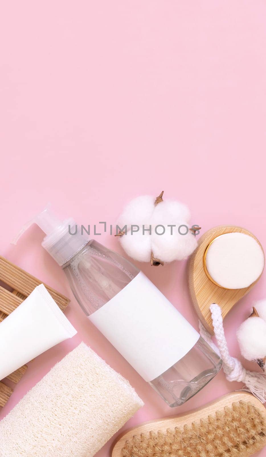 Homemade organic cosmetics in tubes and bottles and eco friendly accessories on pink flat lay, copy space. Top view of natural beauty products for hair and skin care