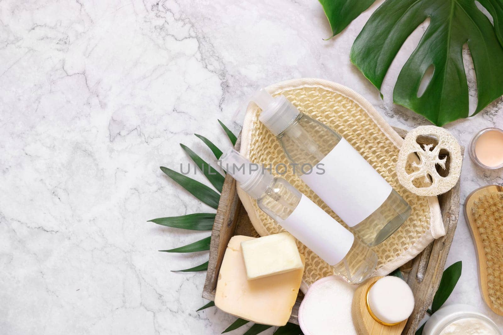 Homemade organic cosmetics and eco friendly accessories near monstera leaves flat lay, copy space. Brand packaging mockup. Natural beauty products for hair and skin care, Top view