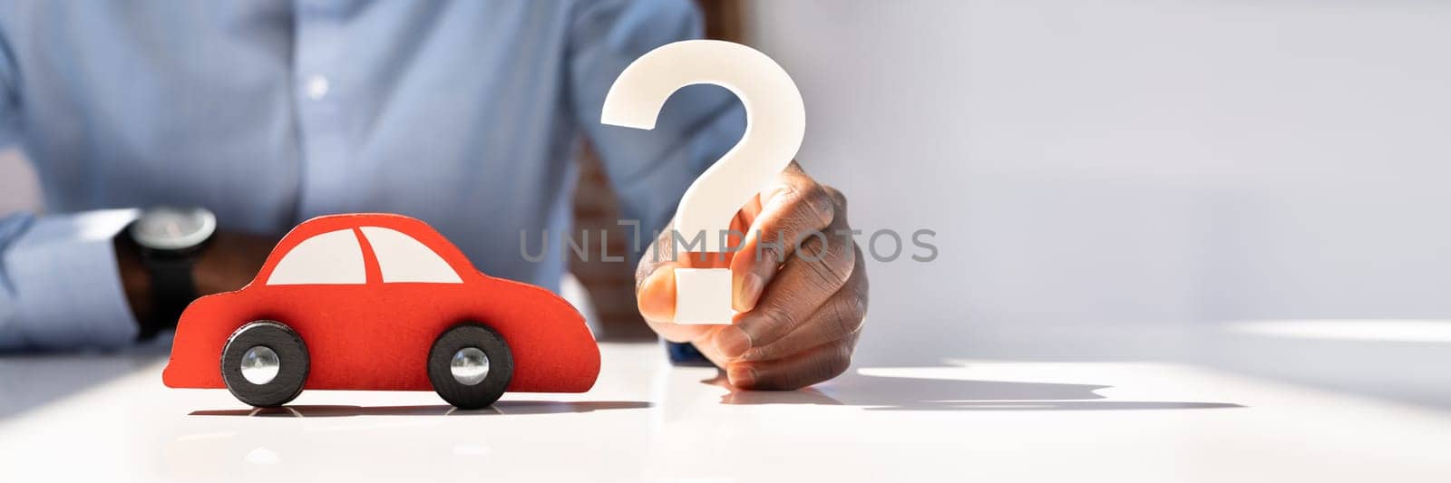 Person Hand Holding Question Mark Next To Car Model