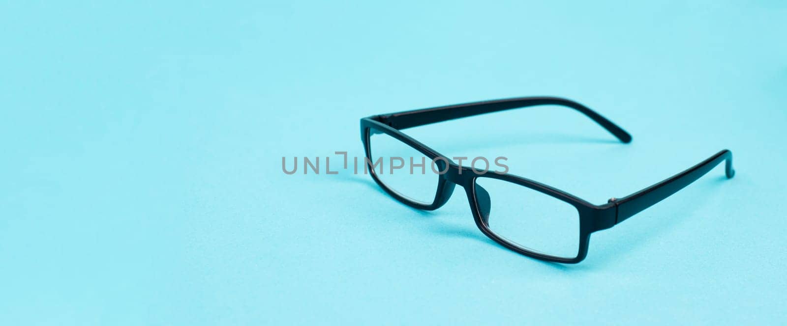 Glasses with a black frame on a blue background, copy space for text