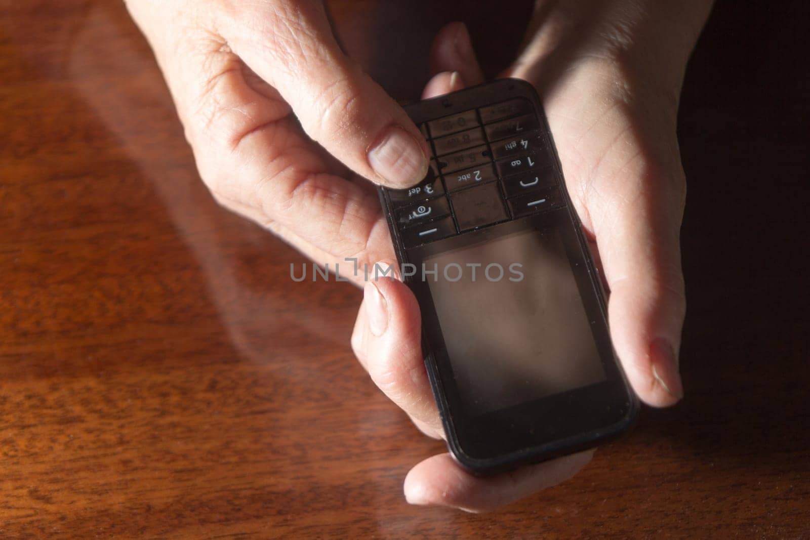 Old woman's hands on an old buttoned phone