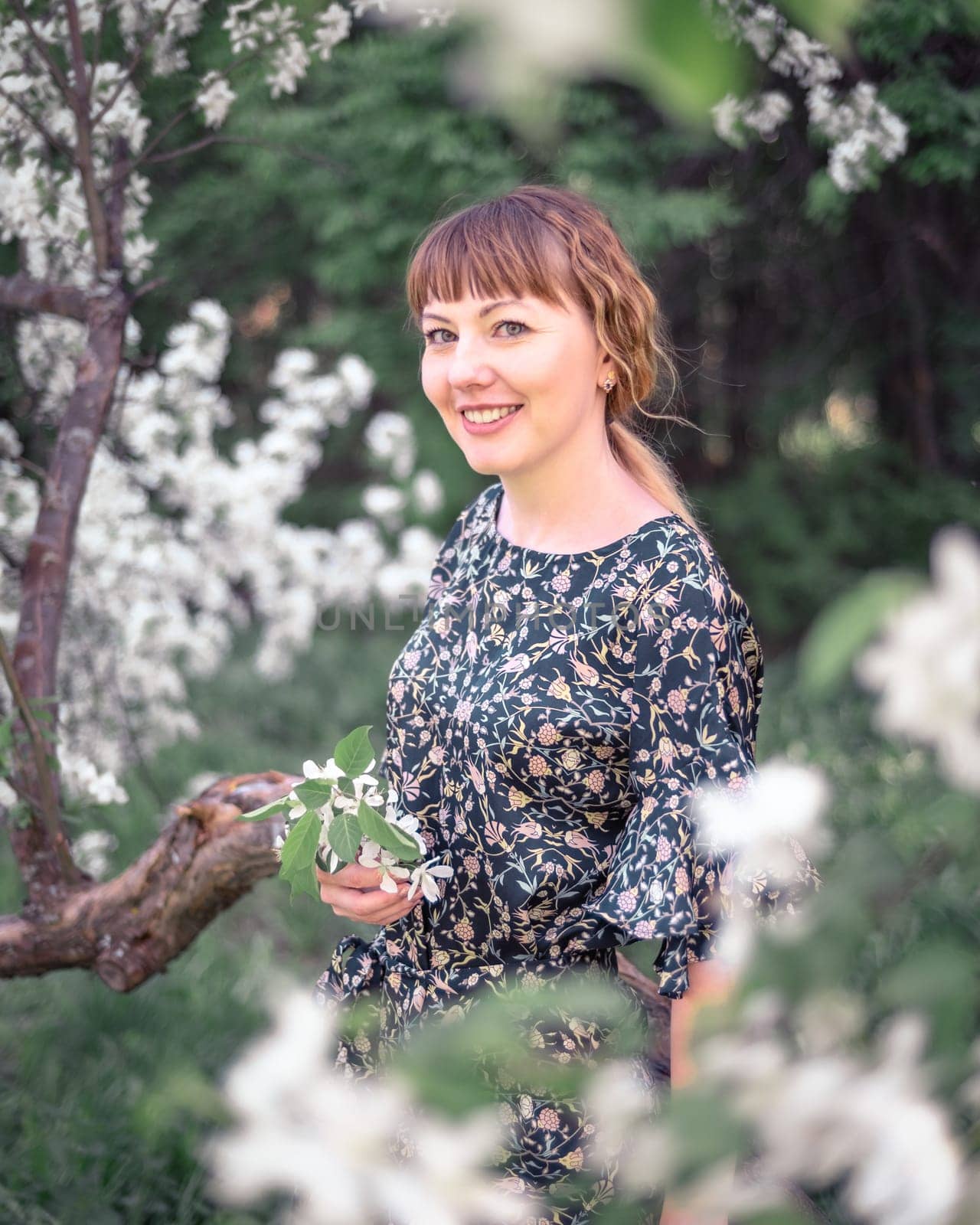 Young woman portrait on blooming apple trees background
