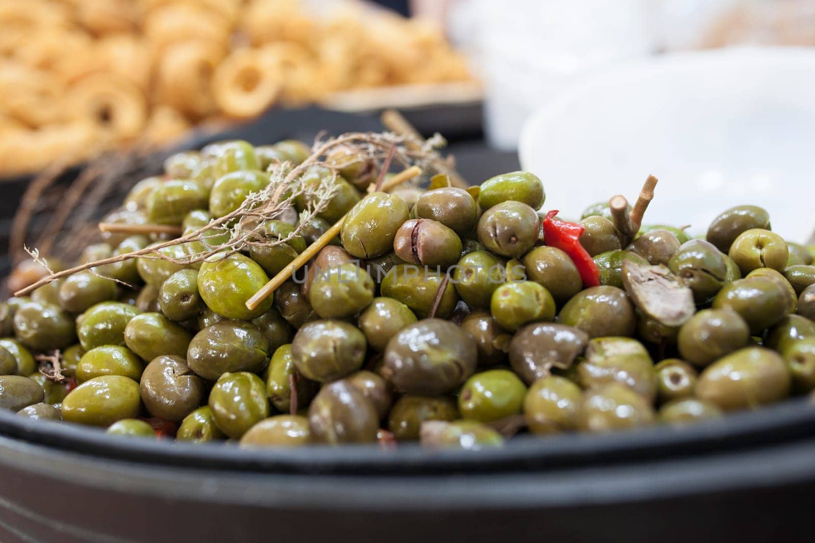 Green crushed marinated olives. Delicious pickled snack displayed plastic basket
