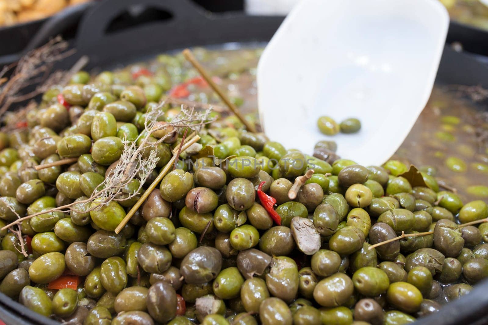 Green crushed marinated olives. Delicious pickled snack displayed plastic basket