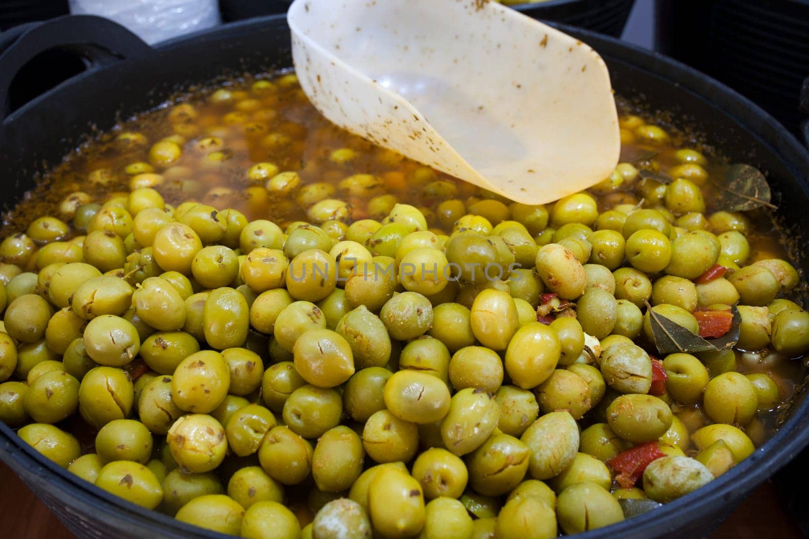 Crushed marinated olives. Delicious pickled snack displayed plastic basket