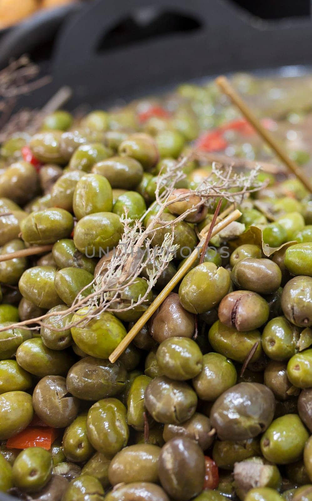 Green crushed marinated olives. Delicious pickled snack displayed plastic basket