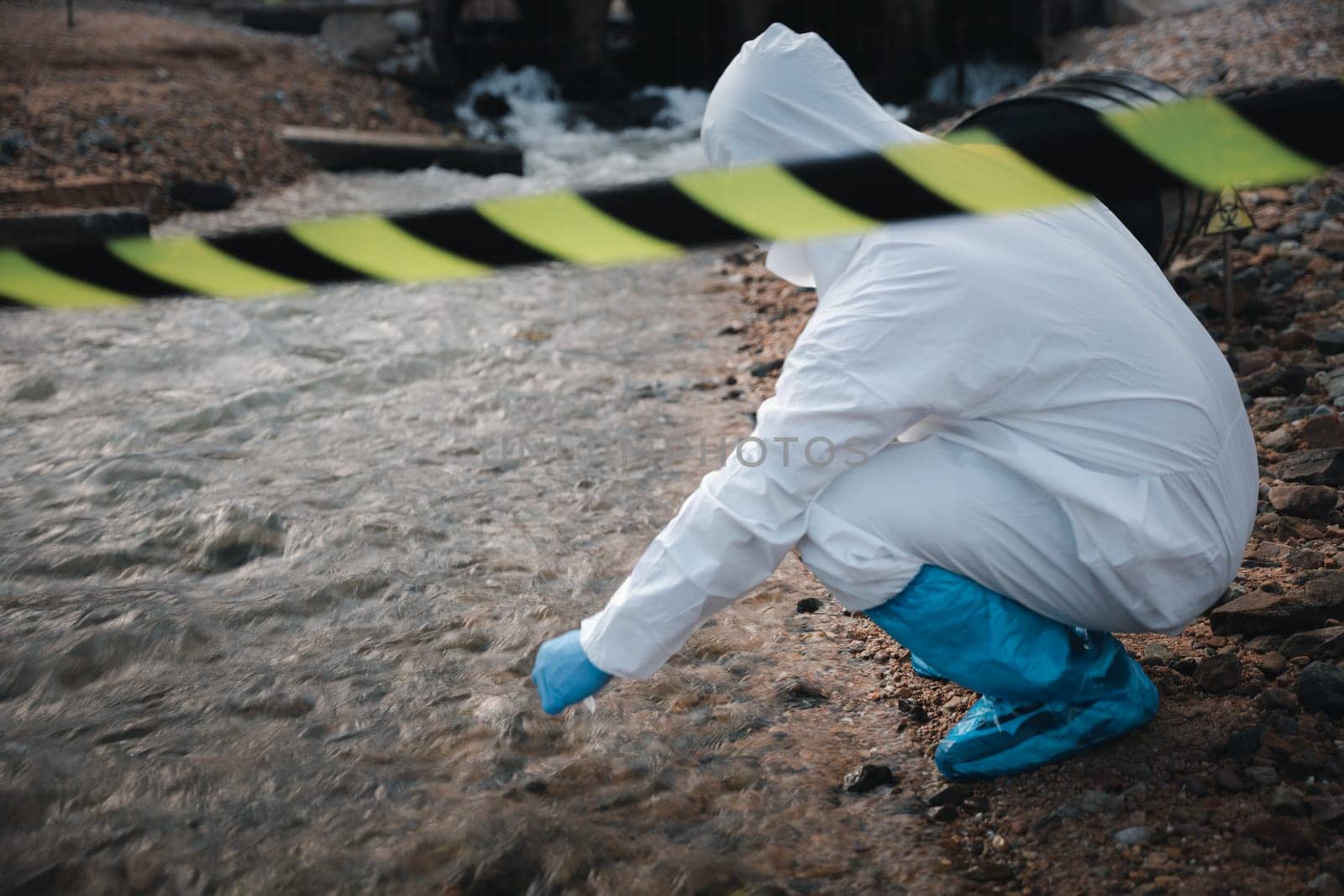 Ecologist sampling water from the river with test tube, Scientist or Biologist in a protective suit and protect mask collects sample of waste water from industrial for analyze, problem environment