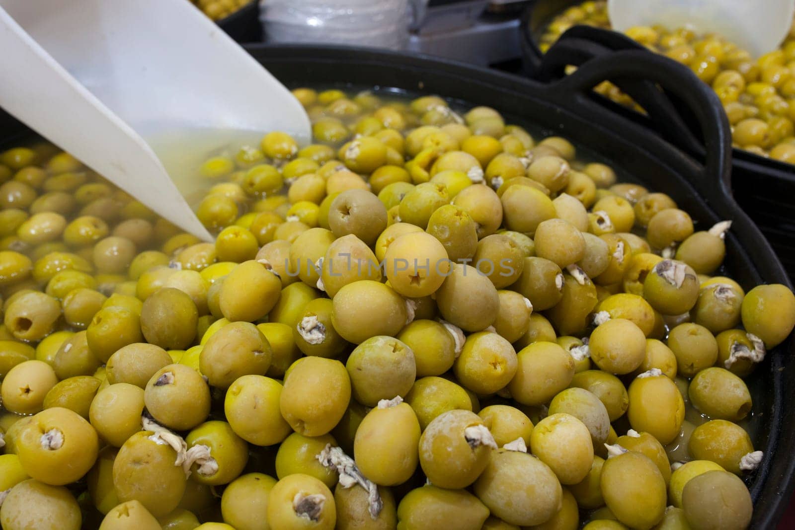 Pickled olives stuffed with vinegar pickled anchovies. Delicious pickled snack displayed plastic basket