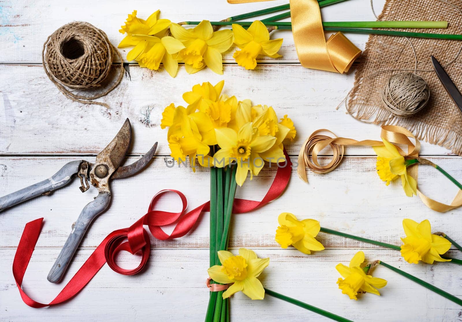 Bouquet of narcissus and gardening tools on rustic wooden table