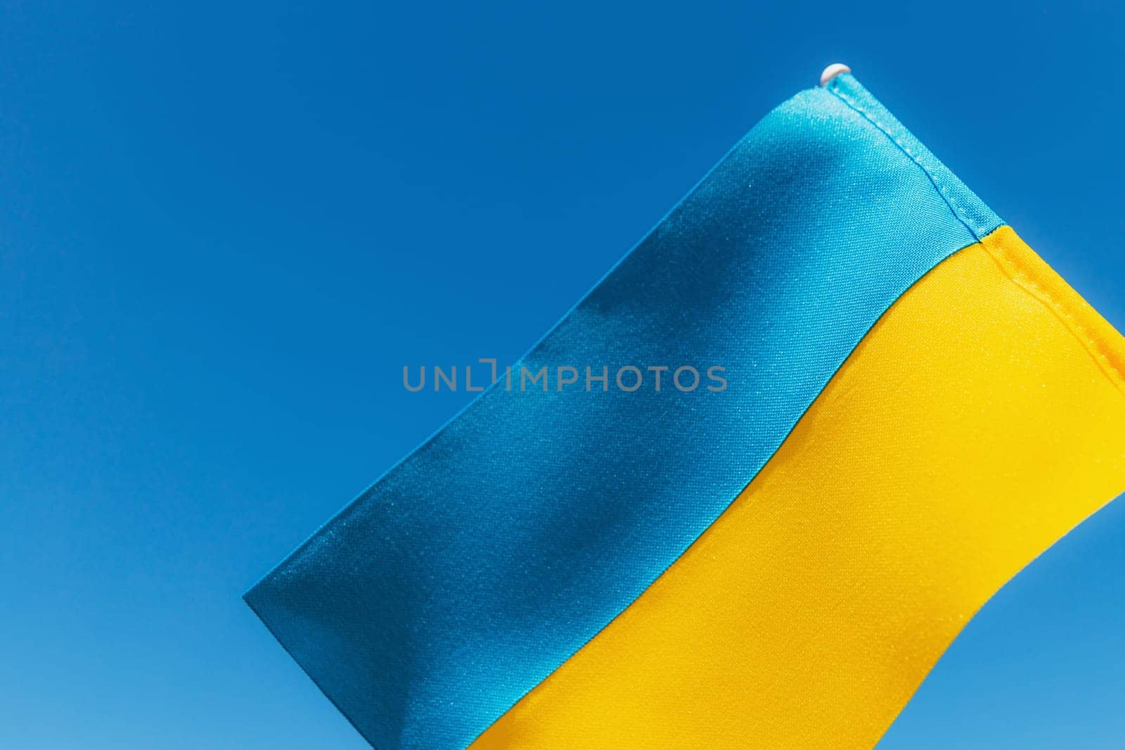 Large bicolor yellow blue Ukrainian state flag, national symbol fluttering, waving in wind against blue sky on sunny day. Kyiv city, capital of Ukraine, Independence Constitution Day, National holiday