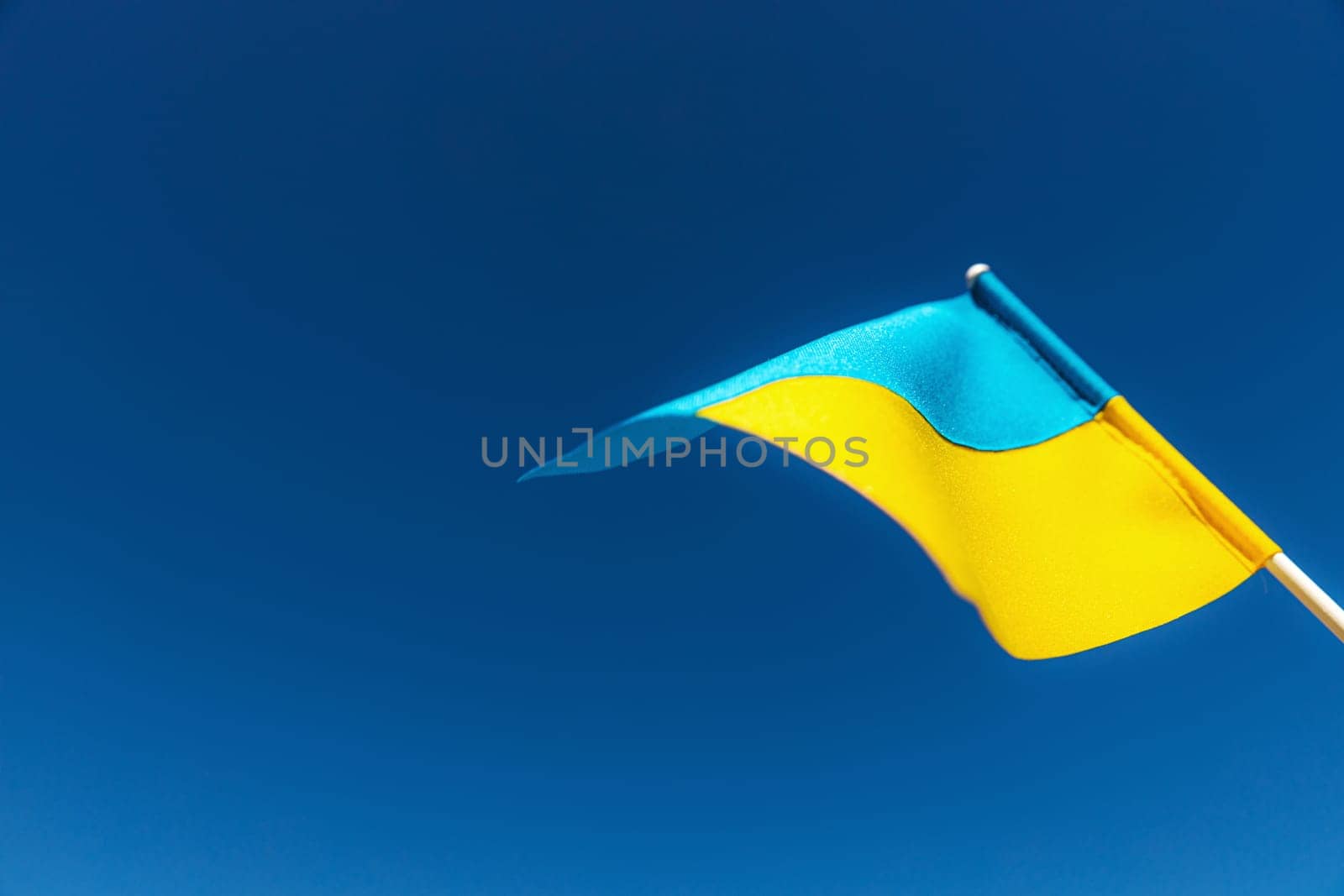 Large bicolor yellow blue Ukrainian state flag, national symbol fluttering, waving in wind against blue sky on sunny day. Kyiv city, capital of Ukraine, Independence Constitution Day, National holiday
